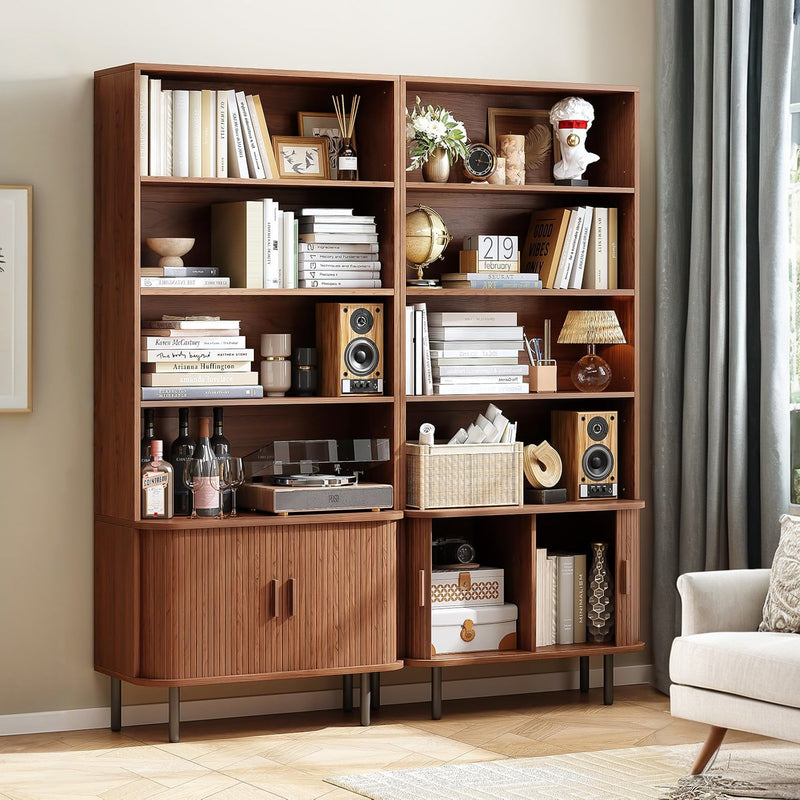 Black tall bookshelf with multiple shelves displaying books, plants, clock, globe, and a lower cabinet with two doors on short legs.